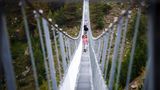 Die Wanderer schauen auf der nur 65 Zentimeter breiten Brücke bei jedem Schritt durch die Gitterroste in den 85 Meter Tiefe.