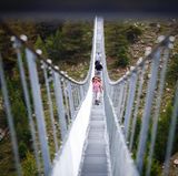 Die Wanderer schauen auf der nur 65 Zentimeter breiten Brücke bei jedem Schritt durch die Gitterroste in den 85 Meter Tiefe.