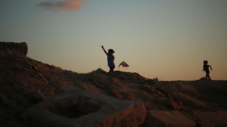Urlaub: Zwei Kinder spielen mit einem Drachen am Strand