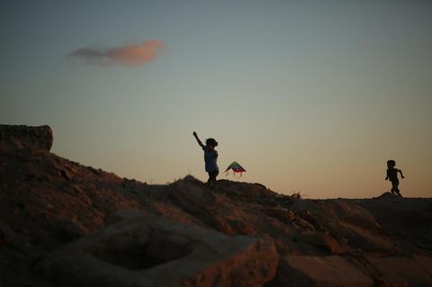Urlaub: Zwei Kinder spielen mit einem Drachen am Strand