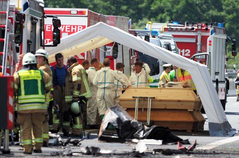 Feuerwehr und Polizei steht am Unfallort. Mehrere Särge werden unter einem Zelt bereitgestellt.