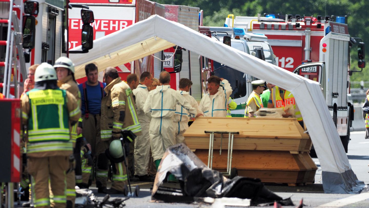Feuerwehr und Polizei steht am Unfallort. Mehrere Särge werden unter einem Zelt bereitgestellt.