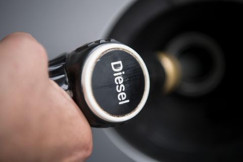 Ein Hand hält einen Tankrüssel mit der Aufschrift "Diesel" in den Tankstutzen eines silbergrauen Autos