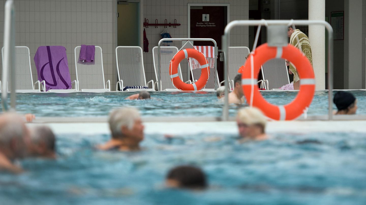 Mehrere ältere Personen schwimmen in einem Hallenbad.