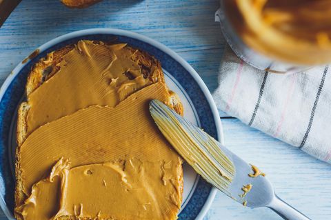 Erdnussbutter klingt erstmal nicht gesund. Sie ist sehr fettig, enthält aber mehr ungesättigte als gesättigte Fettsäuren und gilt daher als guter Lieferant für gesunde Fette. Zudem sind in Erdnüssen Proteine und Ballaststoffe enthalten. Die in der Erdnussbutter enthaltenen ungesättigten Fettsäuren können das ungesunde LDL-Cholesterin im Blut reduzieren und Herzerkrankungen vorbeugen. Natürlich gilt das nur für die Erdnussbutter ohne Zuckerzusätze und mit vollem Fettgehalt. Dann gilt: Zugreifen!