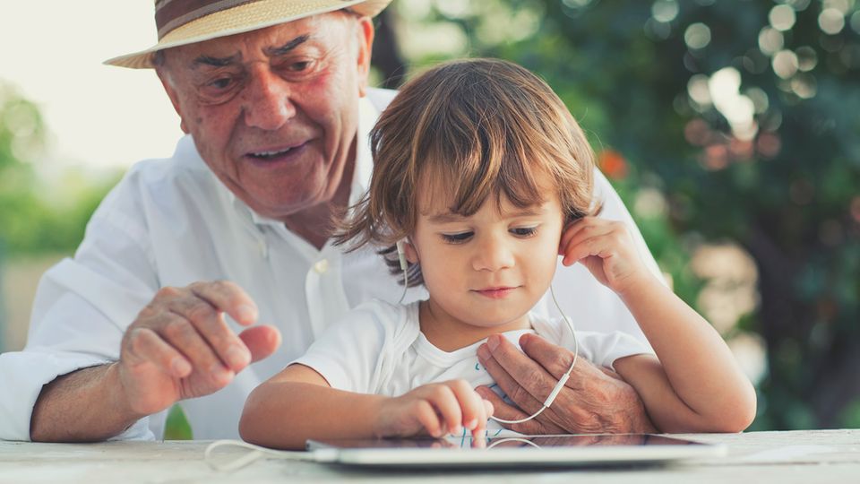 Großvater und Enkel schauen auf ein Tablet
