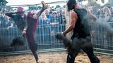 Zwei Männer mit Gasmasken kämpfen bei einer Cagefight-Show auf dem Festivalgelände gegeneinander