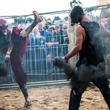Zwei Männer mit Gasmasken kämpfen bei einer Cagefight-Show auf dem Festivalgelände gegeneinander