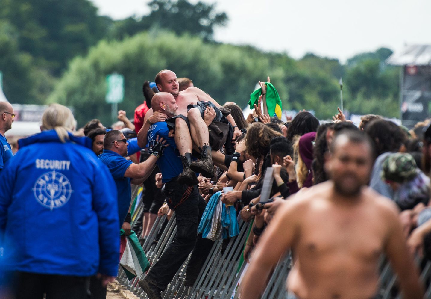 Abtransport: Securityleute tragen einen Festivalbesucher über eine Absperrung vor der Bühne