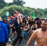 Abtransport: Securityleute tragen einen Festivalbesucher über eine Absperrung vor der Bühne