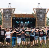 Festivalbesucher tanzen, Arm in Arm, auf dem Festivalgelände vor der Wackinger Stage