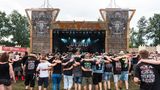 Festivalbesucher tanzen, Arm in Arm, auf dem Festivalgelände vor der Wackinger Stage