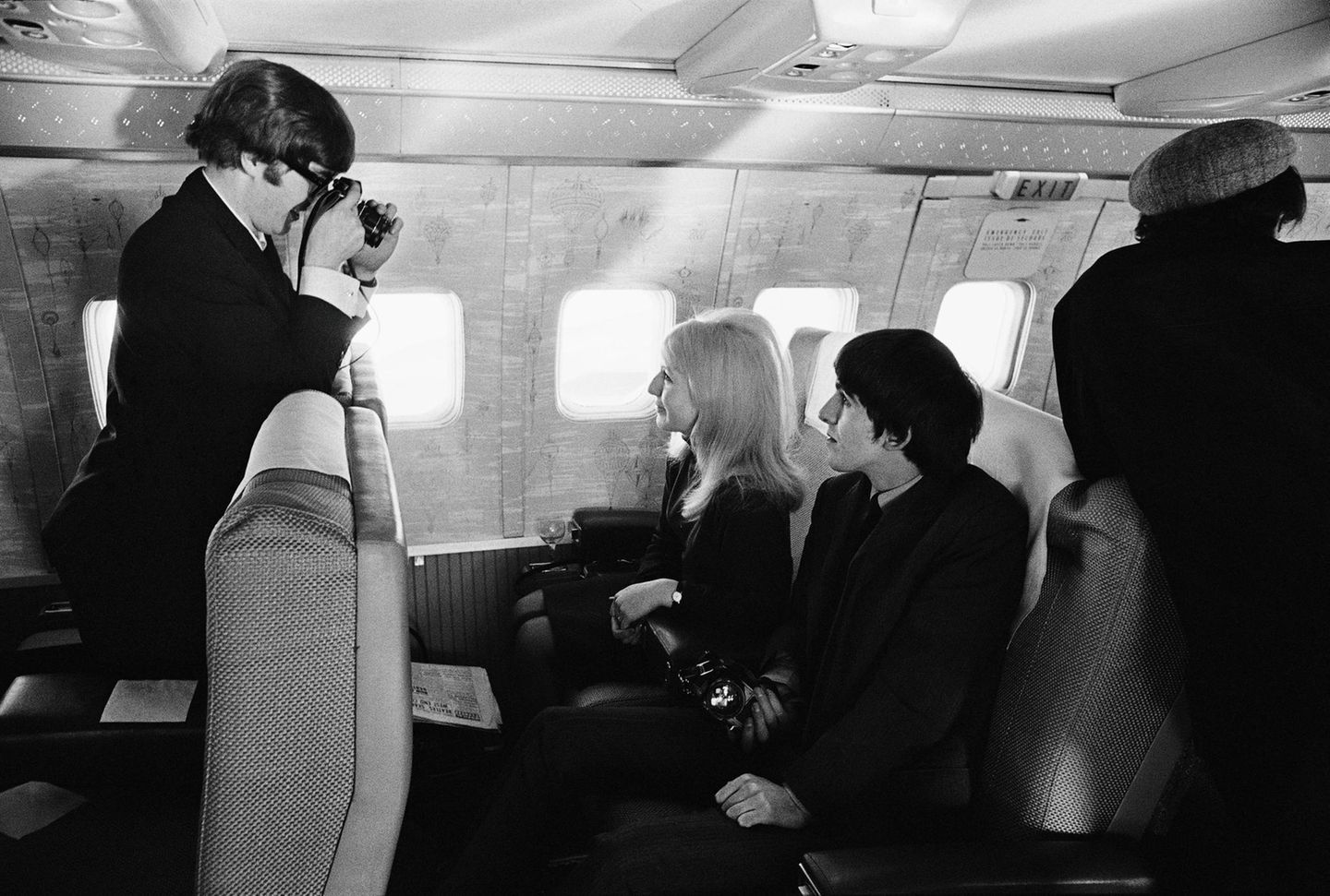 Mit im Flieger nach New York saß auch John Lennons damalige Frau Cynthia. Der Beatle fotografiert sie neben George Harrison sitzend.