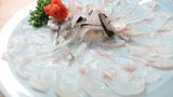 Kugelfisch oder die Leibspeise Fugu     Der Mythos des Kugelfischs ist altbekannt und wurde in vielen Hollywood-Produktionen als Mordwaffe eingesetzt. Nicht ganz ungefährlich - denn ein falscher Schnitt kann ganze Armeen lahmlegen. Im wahrsten Sinne des Wortes. Das Gift Tetrodotoxin (TTX), das sich in Haut, Leber und Eierstöcken des Fisches befindet, nicht aber im Muskelfleisch, wirkt auf die Körpernerven - und zwar so sehr, dass Opfer vollständig gelähmt sind und sich weder bewegen noch sprechen können. Fatal, denn die Vergifteten bleiben bei Bewusstsein, während die Lähmung einen Atemstillstand oder einen Herzstillstand hervorrufen kann. Es gibt aber auch Gegenmaßnahmen: Wenn die Atmung und der Kreislauf in Gang gehalten werden, klingen die Symptome nach 24 Stunden ab. Alle Fugu-Liebhaber können aber aufatmen: Mittlerweile werden Kugelfische zum Verzehr gezüchtet, die kein Tetrodotoxin enthalten - so kann gefahrlos reingebissen werden.