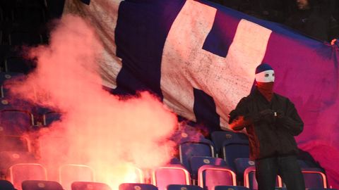 Vermummter Hooligan vor brennendem Banner von Hertha BSC auf den Rängen des Ostsee-Stadions in Berlin