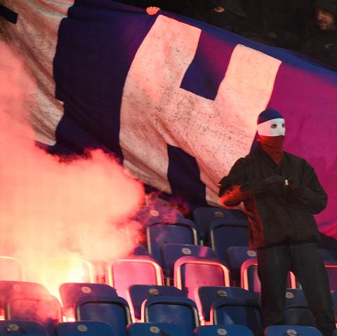 Vermummter Hooligan vor brennendem Banner von Hertha BSC auf den Rängen des Ostsee-Stadions in Berlin