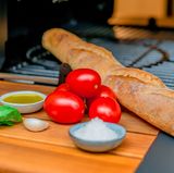 Was Sie für Bruschetta vom Grill brauchen? Ein Ciabatta oder Baguette, Fleischtomaten, eine Knoblauchzehe, Basilikum, Olivenöl und etwas Salz. 