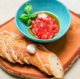 Hacken Sie die Tomaten ganz fein und geben Sie Olivenöl und Salz darüber. Schälen Sie die Knoblauchzehe und zupfen Sie sich etwas Basilikum zurecht. Das Ciabatta oder Baguette in Scheiben schneiden.