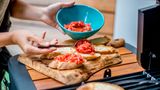 Verteilen Sie die Tomaten nun auf den Knoblauch-Brot-Hälften.