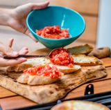 Verteilen Sie die Tomaten nun auf den Knoblauch-Brot-Hälften.