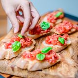 Fürs Auge und den Geschmack verteilen Sie jeweils zwei Basilikumblättchen auf den Bruschette.