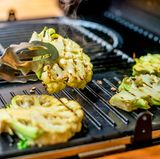 Grillen Sie den in Steaks geschnittenen Blumenkohl bei starker Hitze, bis das Gemüse von beiden Seiten Farbe annimmt.