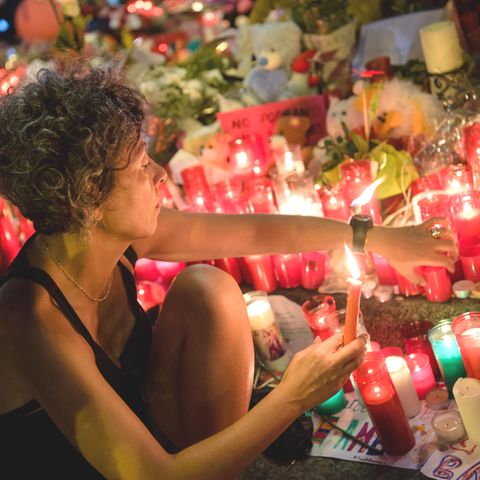 Eine Frau zündet am Anschlagsort auf der Flaniermeile Las Ramblas in Barcelona erloschene Kerzen wieder an Eine Frau zündet am Anschlagsort auf der Flaniermeile Las Ramblas in Barcelona erloschene Kerzen wieder an