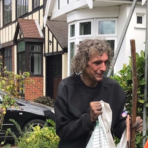 Der obdachlose John räumt mit einem Lächeln im Gesicht einen Garten auf
