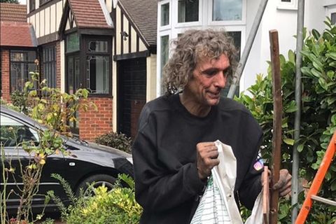 Der obdachlose John räumt mit einem Lächeln im Gesicht einen Garten auf