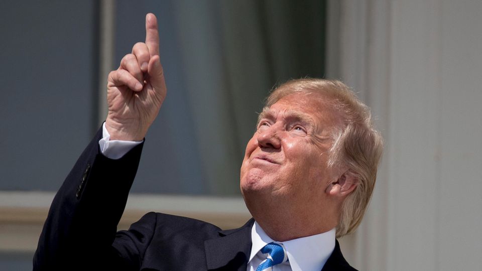Donald Trump zeigt vor der Sonnenfinsternis mit dem Finger in Richtung Sonne und trägt dabei keine Sonnenbrille