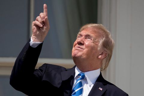 Donald Trump zeigt vor der Sonnenfinsternis mit dem Finger in Richtung Sonne und trägt dabei keine Sonnenbrille