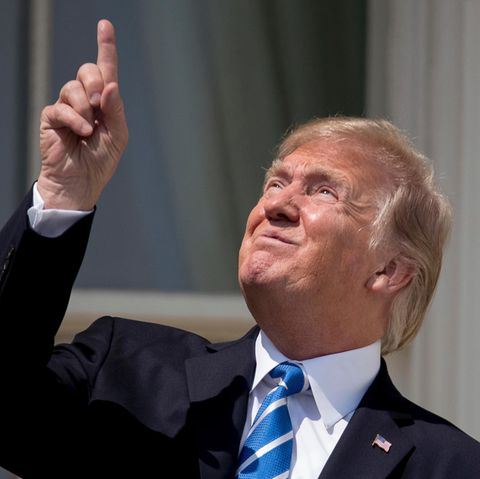Donald Trump zeigt vor der Sonnenfinsternis mit dem Finger in Richtung Sonne und trägt dabei keine Sonnenbrille