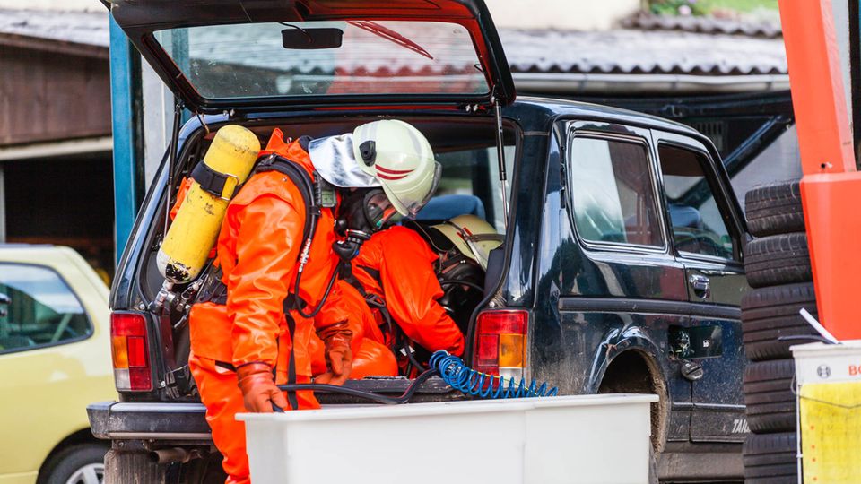In speziellen Chemieschutzanzügen holen Feuerwehrleute in Schlangenbad das Wasserstoffperoxidaus dem Tank eines Lada