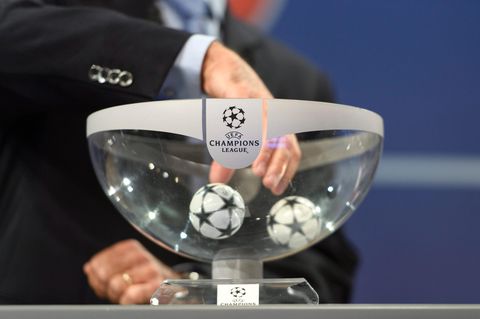 Eine Hand greift in einen durchsichtigen Lostopf mit Champions League Logo. In der Schale liegen noch zwei Kugeln.