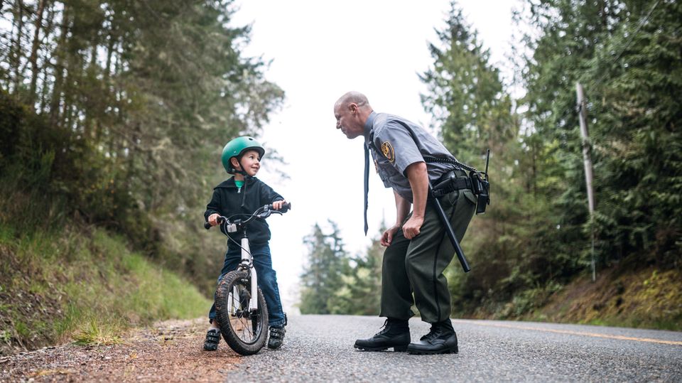 Polizist mit Kind Polizist ermahnt Kind auf einem Fahrrad