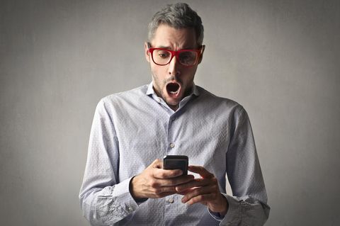 Ein Mann schaut schockiert auf sein Smartphone