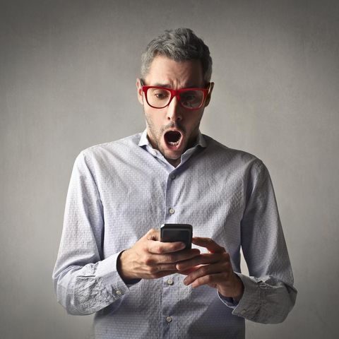 Ein Mann schaut schockiert auf sein Smartphone