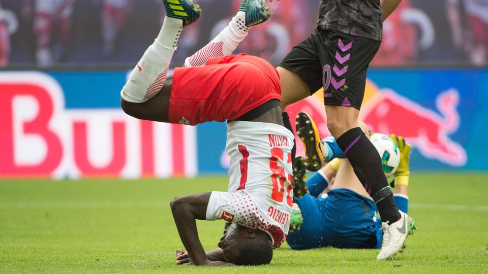 Au: Leipzigs Jean-Kevin Augustin landet nach einem Zusammenstoß mit Freiburgs Torwart Alexander Schwolow auf dem Kopf. Au: Leipzigs Jean-Kevin Augustin landet nach einem Zusammenstoß mit Freiburgs Torwart Alexander Schwolow auf dem Kopf.