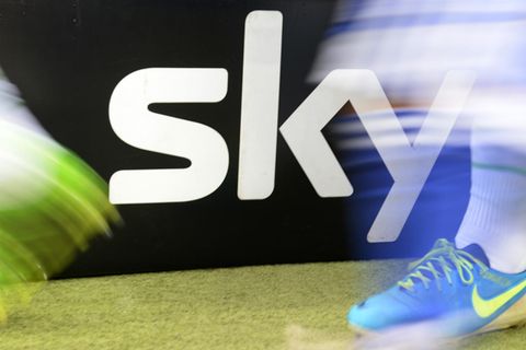 Zwei Fußball-Spieler laufen an einem Sky-Logo neben dem Platz vorbei