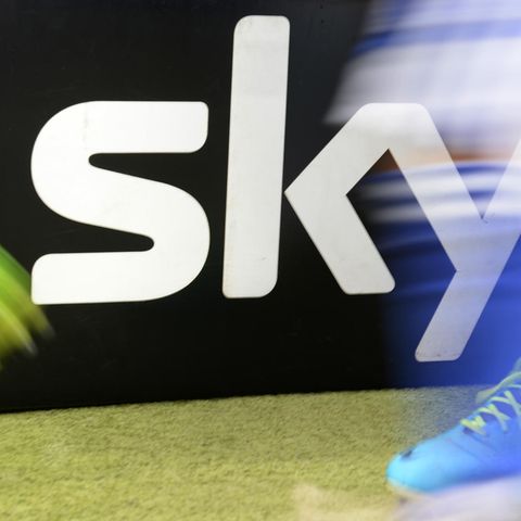 Zwei Fußball-Spieler laufen an einem Sky-Logo neben dem Platz vorbei