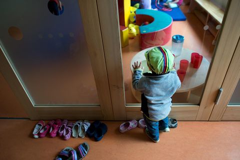Ein Kleinkind steht an einer Glasscheibe in einer Kindertagesstätte in Dresden