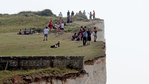 Menschen stehen an den Klippen in der Nähe von Eastbourne, Großbritannien