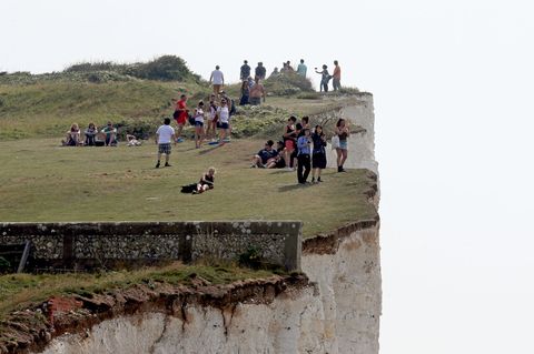 Menschen stehen an den Klippen in der Nähe von Eastbourne, Großbritannien