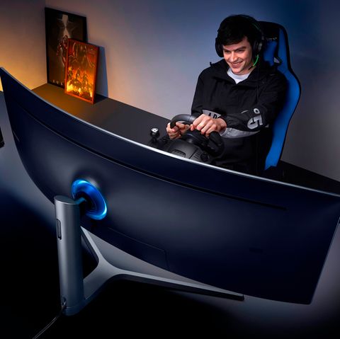 Ein junger Man spielt mit einem Lenkrad auf dem Samsung CHG90 Monitor