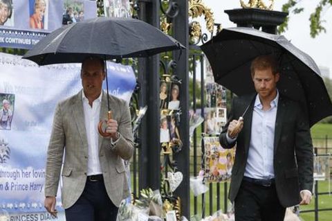 William und Harry schauen sich vor dem Kensington Palast niedergelegte Blumen an