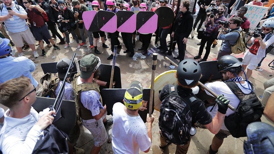Rassismus in den USA: Charlottesville am 12. August: Mit rosa Schilden schützen sich Gegendemonstranten vor gewaltbereiten Rechtsradikalen, eine junge Frau stirbt. Donald Trump spricht später von Gewalt "auf beiden Seiten" Charlottesville am 12. August: Mit rosa Schilden schützen sich Gegendemonstranten vor gewaltbereiten Rechtsradikalen, eine junge Frau stirbt. Donald Trump spricht später von Gewalt "auf beiden Seiten"