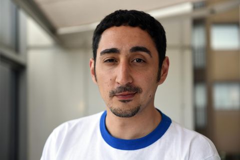 Rapper und Schauspieler Eko fresh schaut in die Kamera. Er trägt ein weißes T-Shirt mit blauem Rundkragen