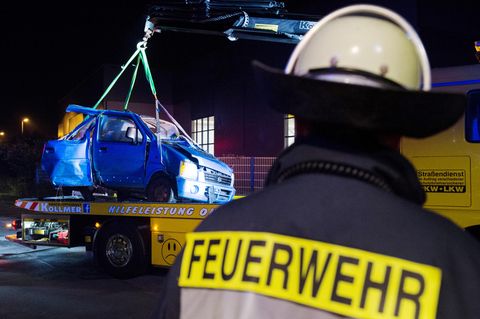Das Fahrzeugwrack wird nach dem Zusammenstoß eines Autos mit einem ICE an der Bahnstrecke bei Bönen in Nordrhein-Westfalen aus einem Gebüsch auf ein Bergungsfahrzeug gehoben. 