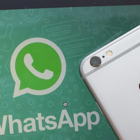 Ein iPhone liegt neben einem Bildschirm mit dem Whatsapp-Logo