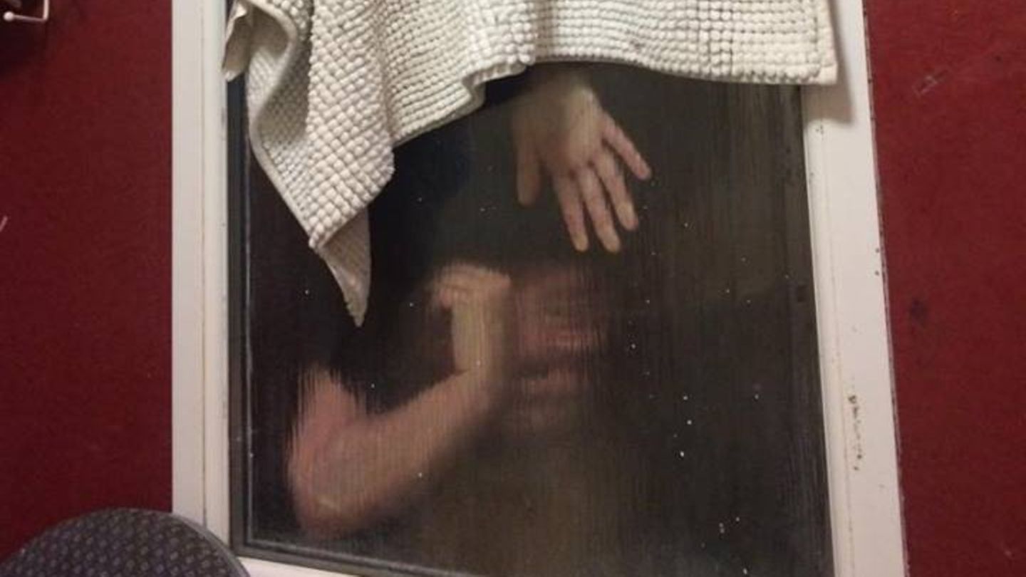 Die junge Frau hängt kopfüber im Fenster